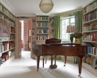Music room with grand piano and bookshelves in Kit Kemp's house
