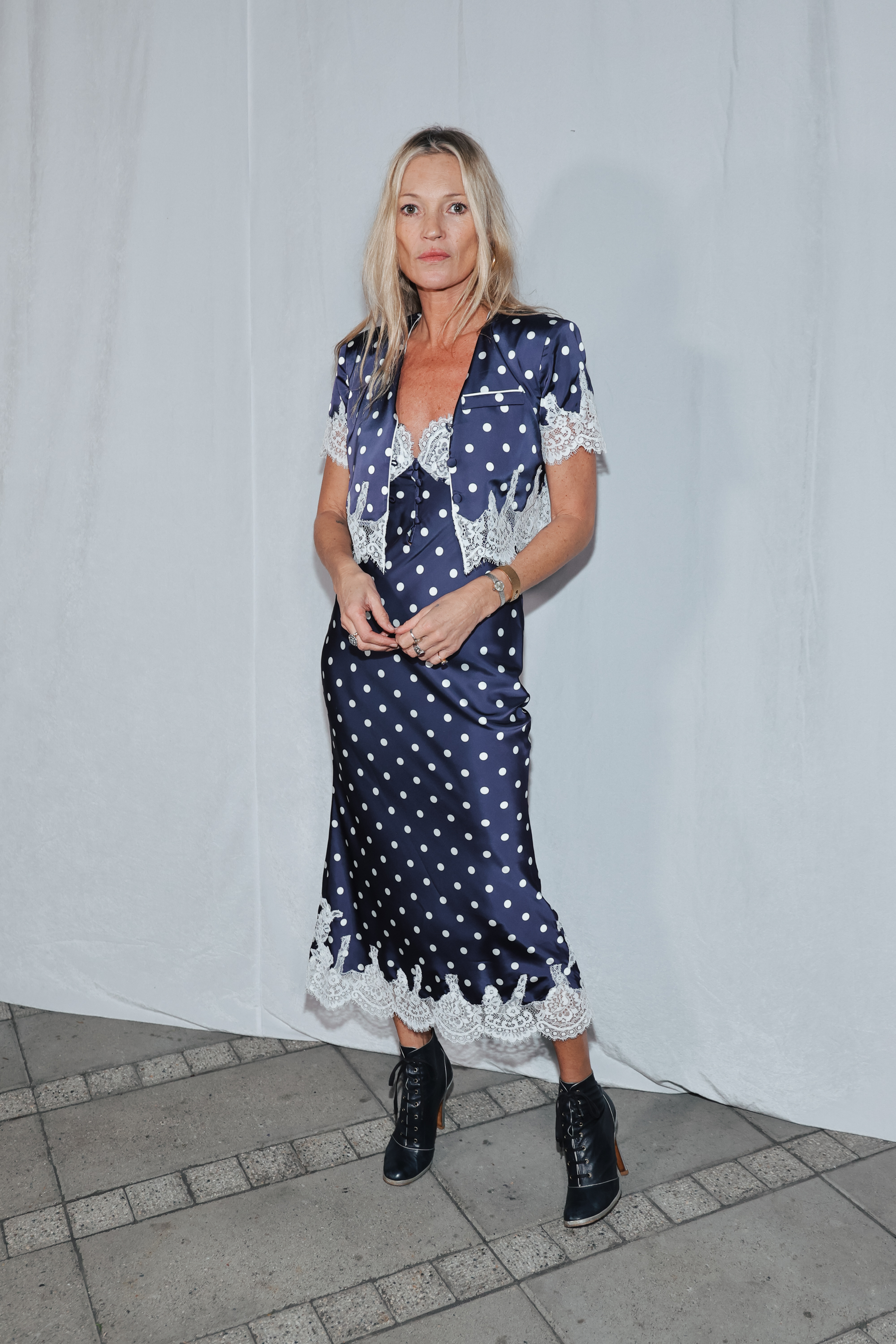 Kate Moss wears a midi-length polka dot dress with heeled lace-up boots.