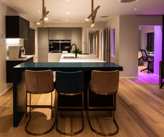 open plan kitchen diner with opening into home office space lit with purple neon LED feature light