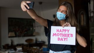 Girl wearing a mask is taking a selfie for mother's day during COVID-19.
