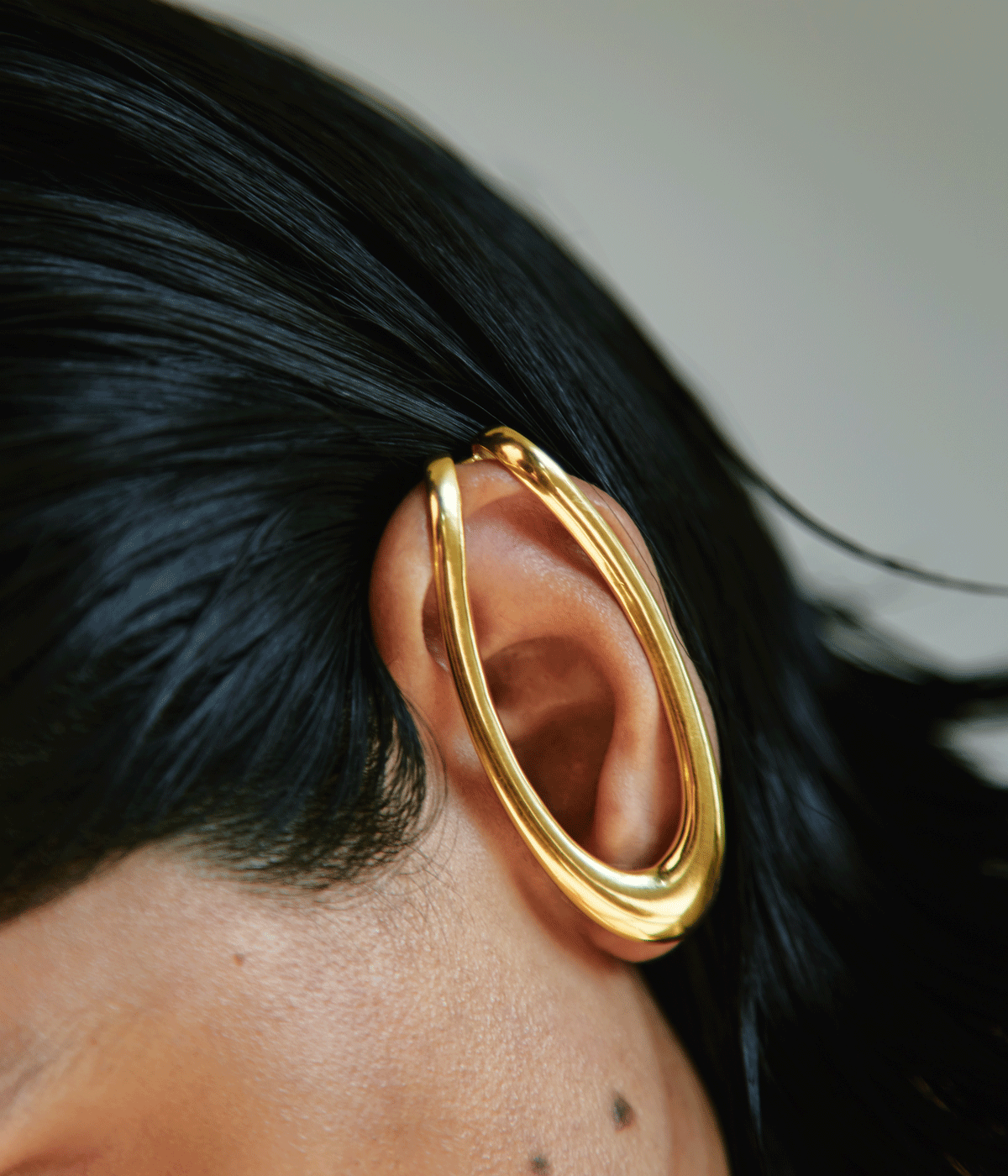 woman wearing gold hooped earring over ear