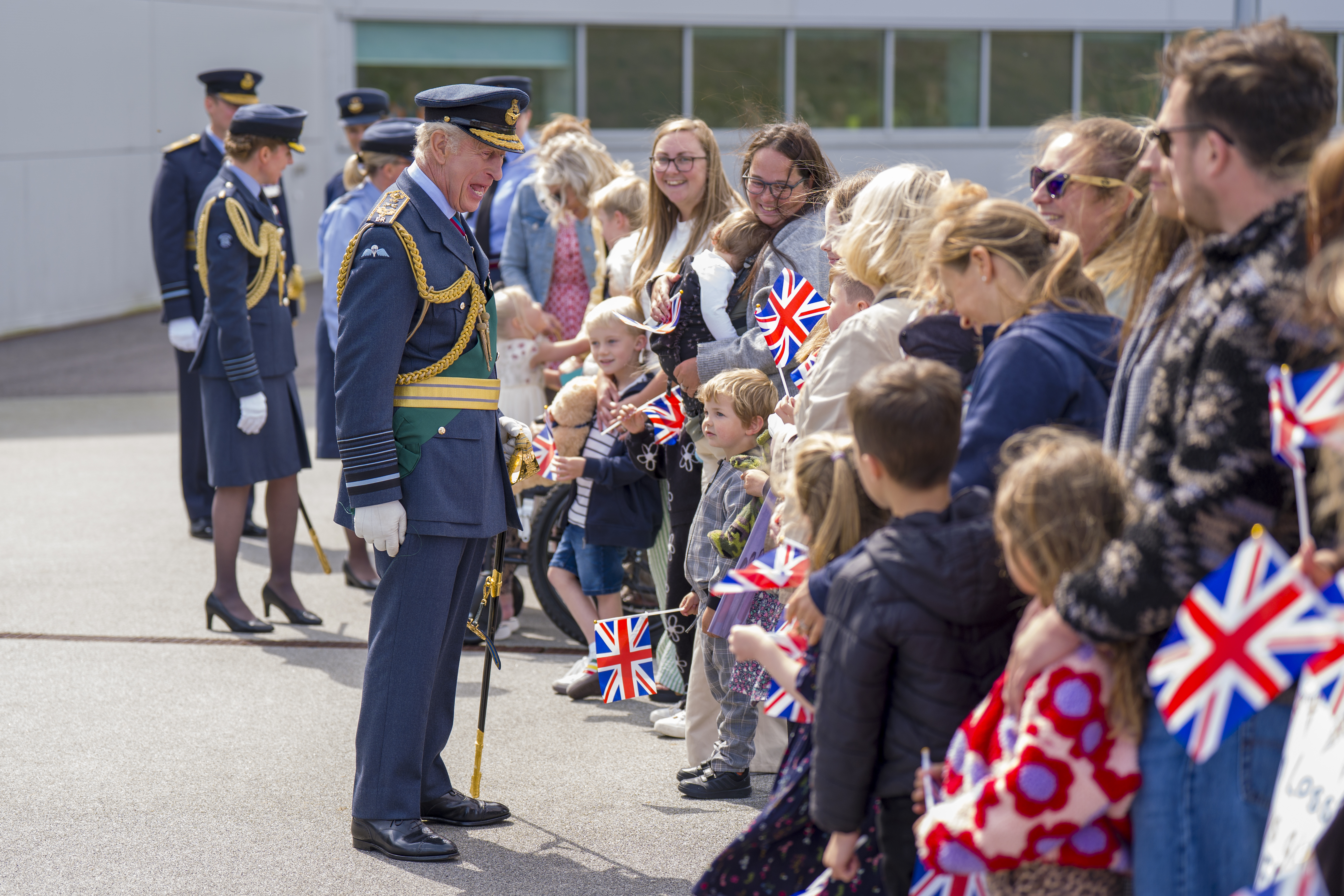 King Charles wears military uniform and meets a crowd of people including an unhappy baby