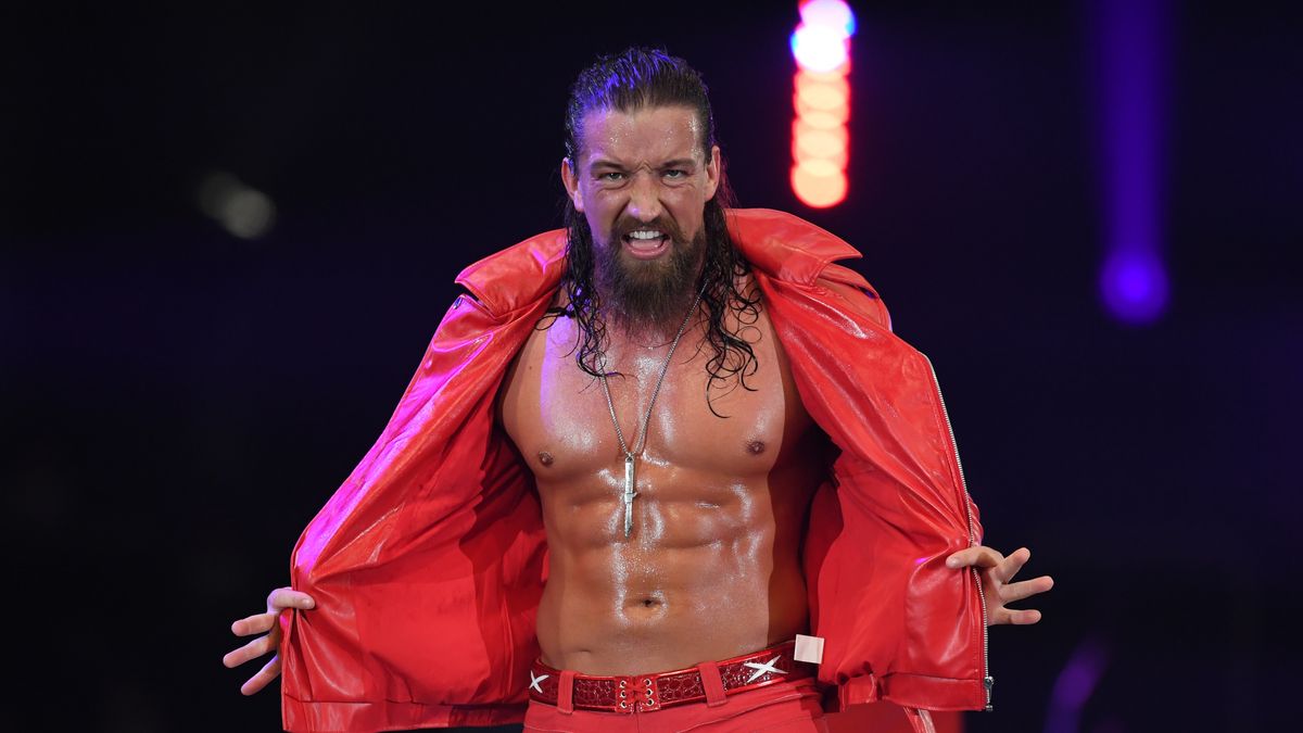 Wrestler Jay White flings open his red PVC jacket to revealed his oiled-up ab muscles ahead of the AEW Full Gear 2023 PPV event. 