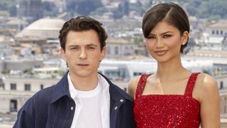 Tom Holland in a blue button down and white tee and Zendaya in a red sparkly tank top with short hair and stud earrings for Spider-Man: Brand New Day photocall.