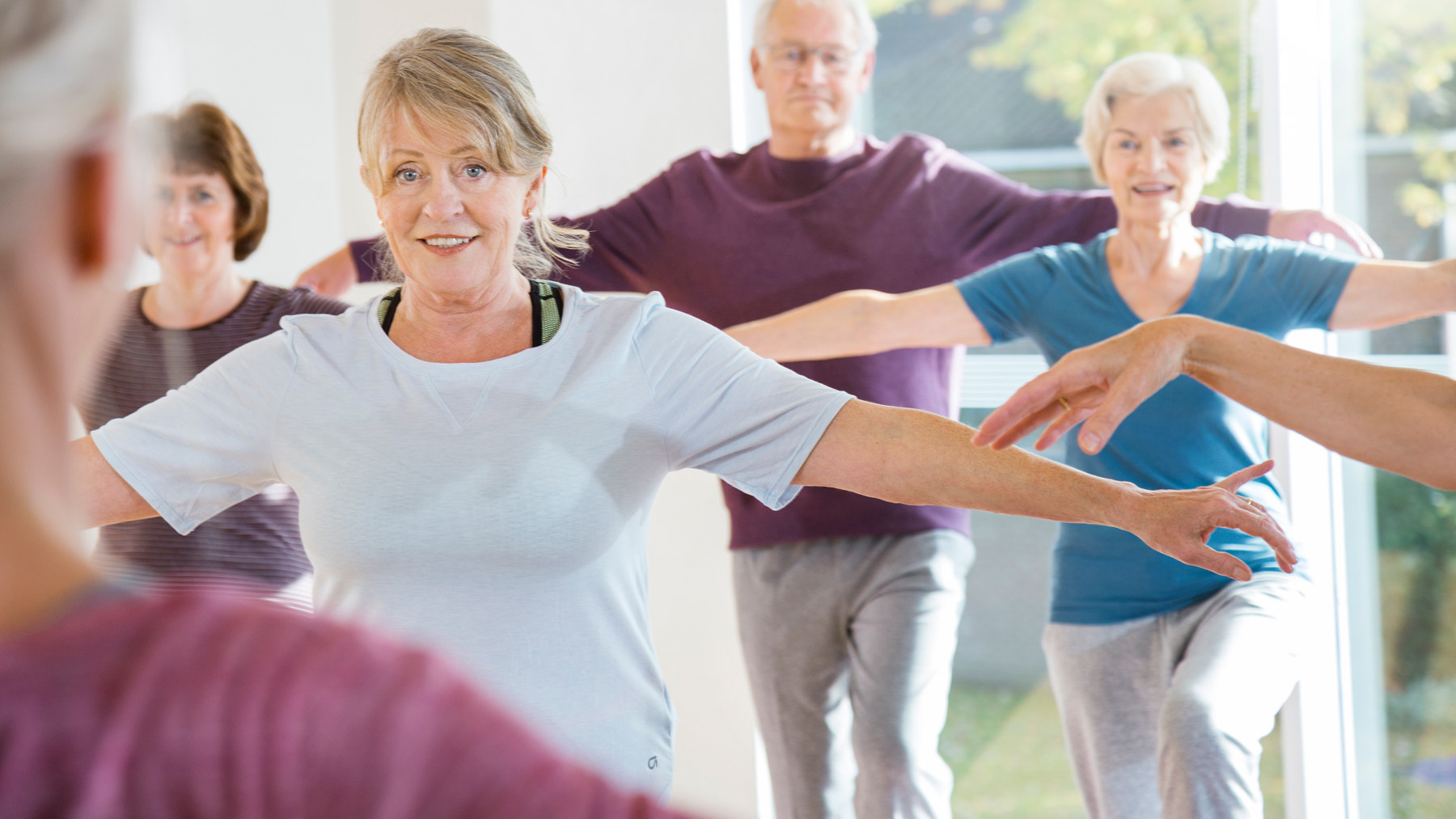 Photo of people in an exercise class balancing as they lift one leg up