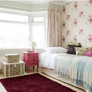 teenagers room with rose wallpaper and floral storage trunks