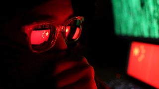 A cyber criminal with the Chinese flag reflected in their glasses