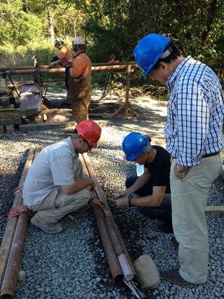 David Goldberg (standing to the right), Paul Olsen (crouching, right) and others fitting together rocks cores after they are taken up from deep underground.