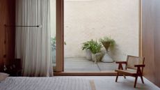 A minimalist bedroom with a door leading out into an outdoor space with potted plants
