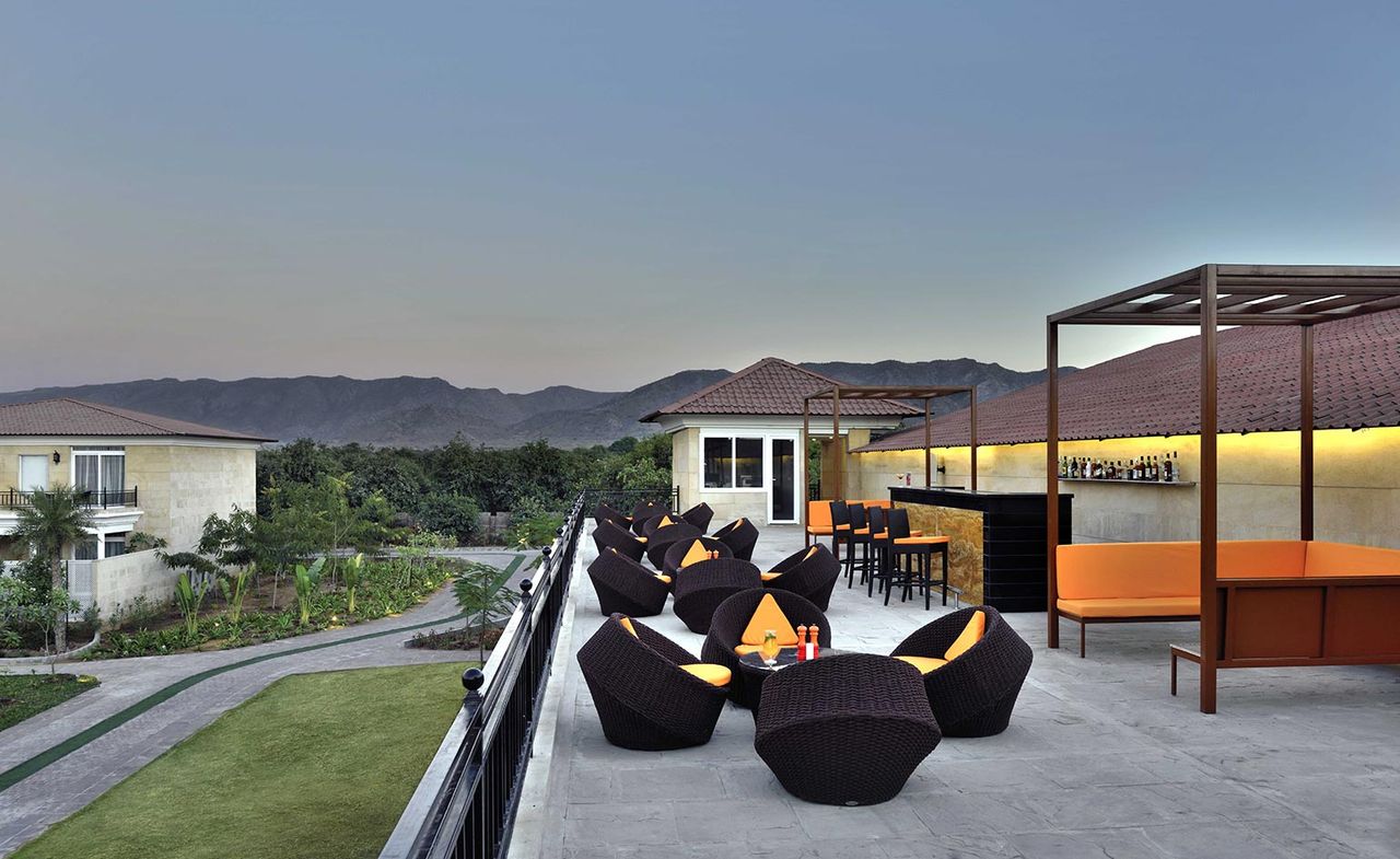 An image of the hotel&#039;s rooftop lounge with sunset views over the Aravali Mountains