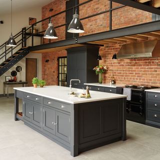 Dark grey kitchen with white countertops and exposed brick wall