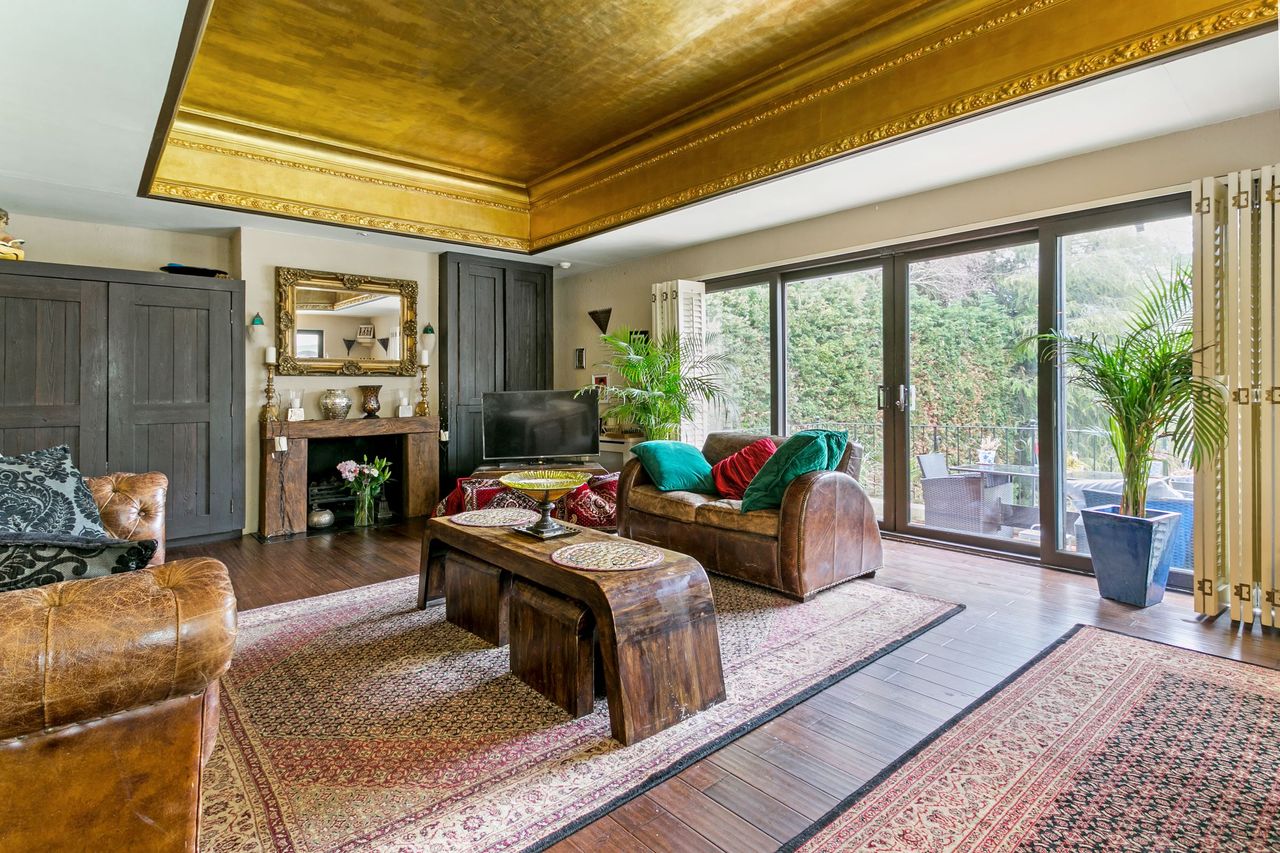 The living room has brown leather sofas and leads out onto the patio and has a black fireplace in the corner.