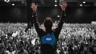 Image of man standing in front of cheering crowd with his hands in the air, and an NBN logo on his back