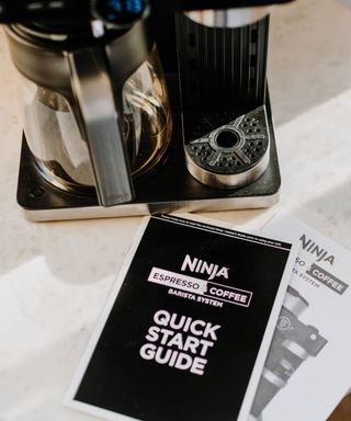 Closeup of Ninja Espresso & Coffee Barista System with instruction manual and quick start guide