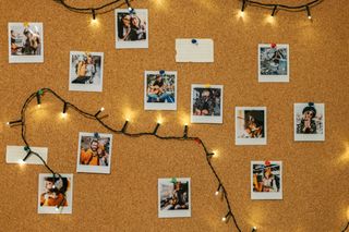 A corkboard with polaroids and fairy lights on.