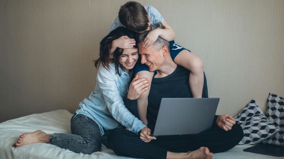 Family looking down at laptop while embracing