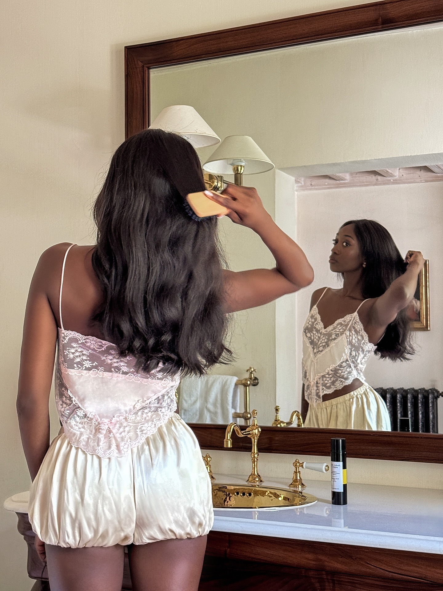 A woman brushing her hair in the mirror.