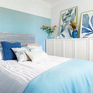 blue and white bedroom with white cupboards and pictures