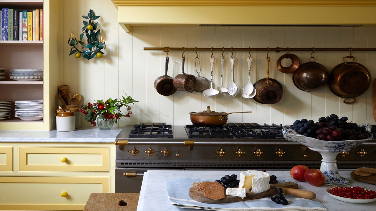 yellow kitchen with saucepans hanging over a range cooker