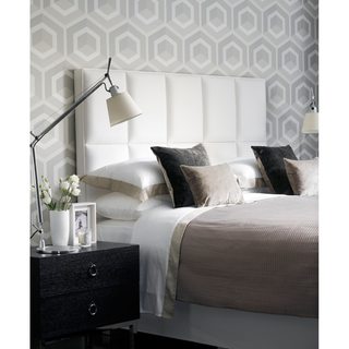 bedroom with hexagonal designed white and grey wall and white bed