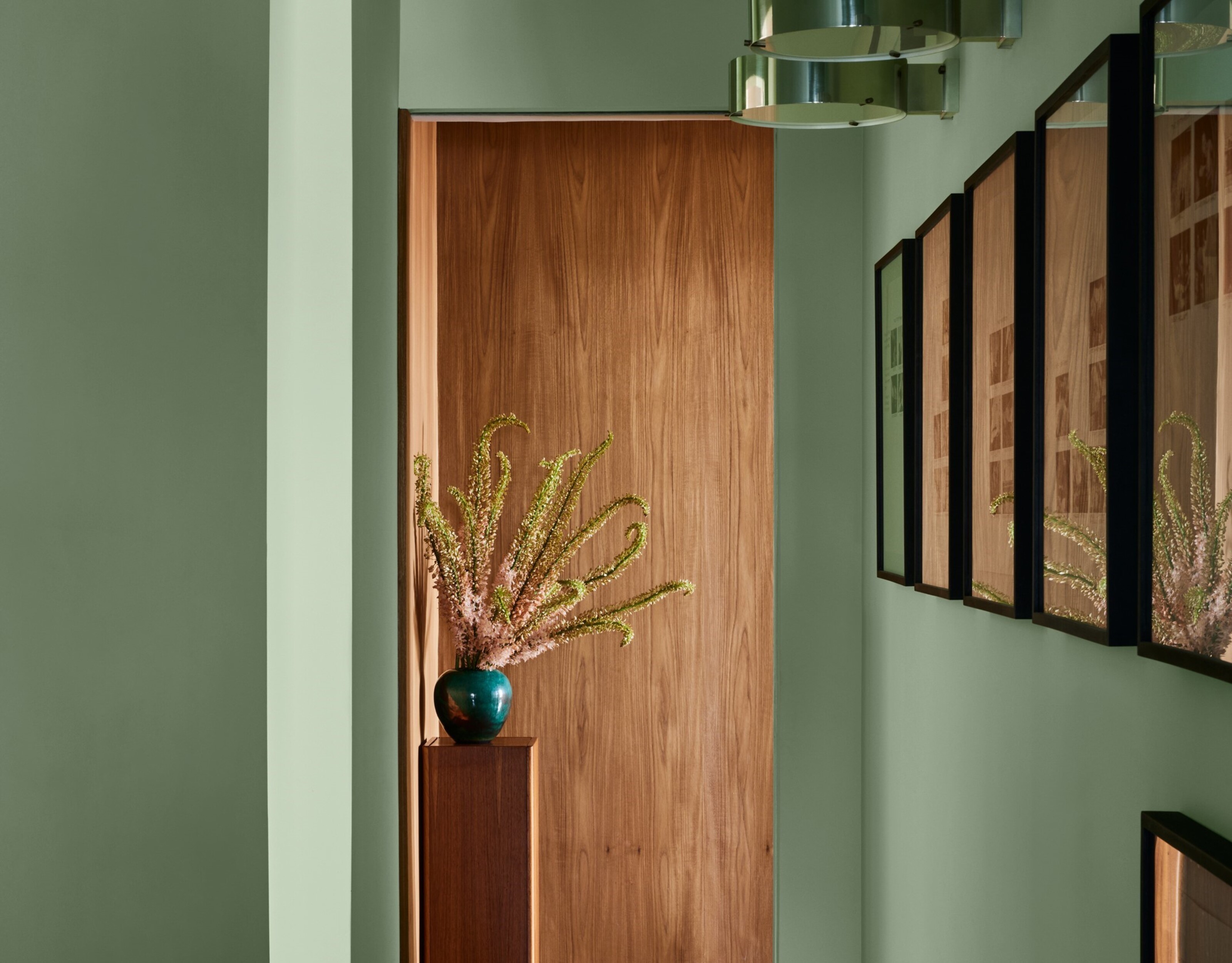 An entryway with wall decor and a vase on a plinth