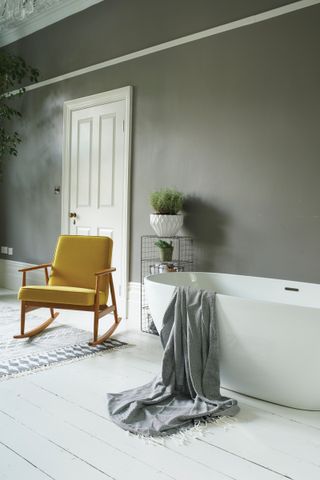 Modern bathroom with freestanding bath, wire unit and yellow mid-century inspired chair