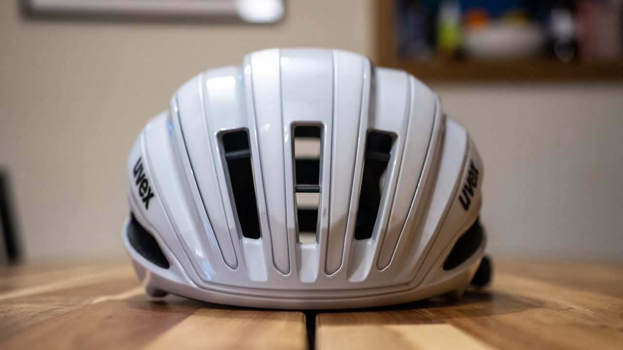 A white Uvex Surge helmet stands on a wooden table