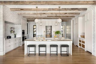 A kitchen with wooden beams, industrial-style lights and tiled walls