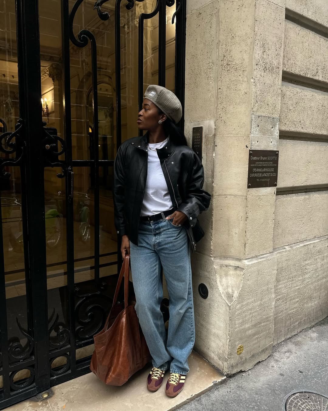 @nlmarilyn wearing jeans, leather jacket, beret, leather shoulder bag, and brown Adidas sneakers,