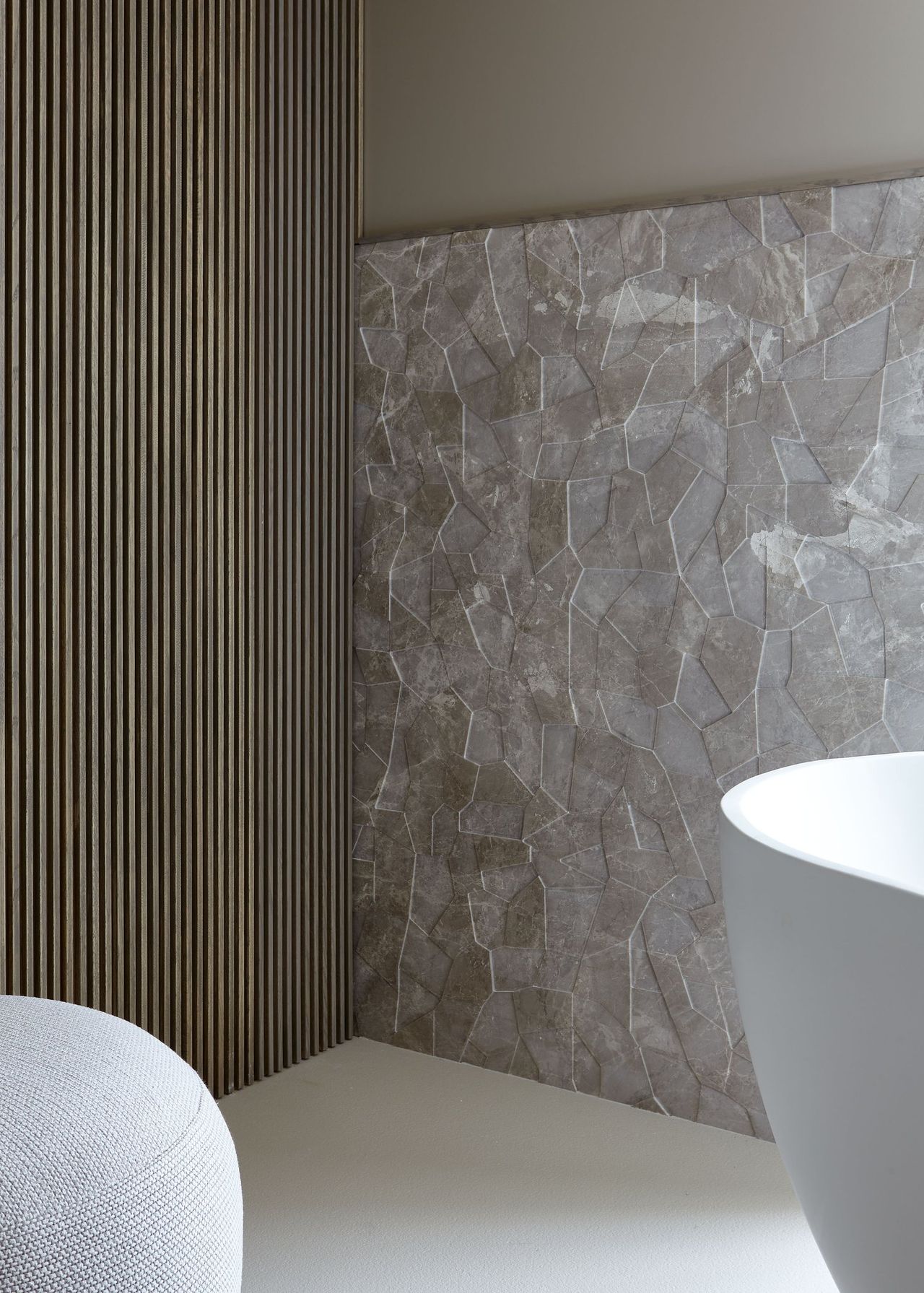 A bathroom features multiple accent walls with organic textures, one of them made of stone, the other, in wood.