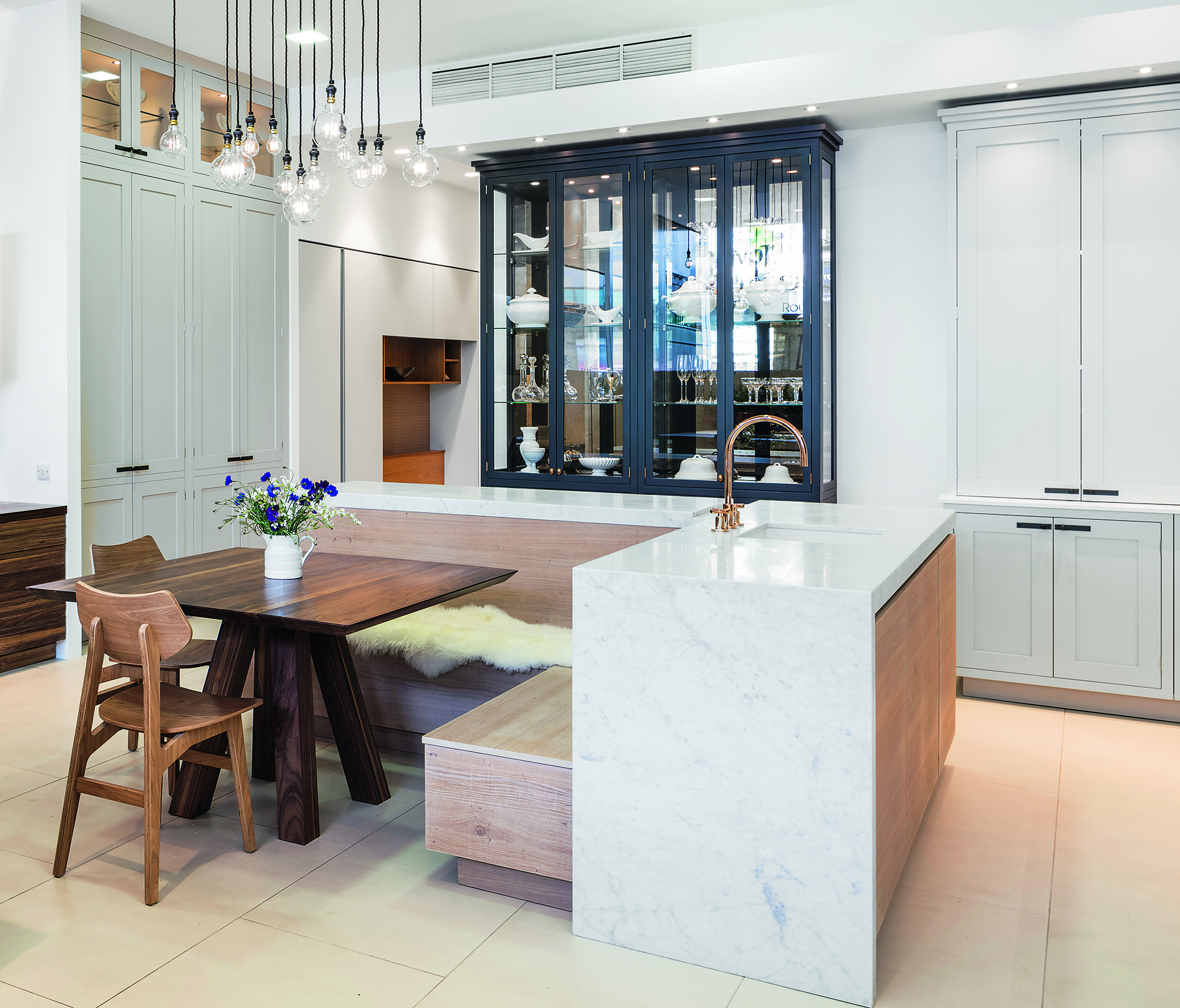 Kitchen island ideas in white marble with wooden banquette seating and a square wooden table.