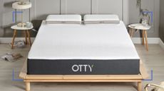 Otty Original Hybrid mattress pictured on a wooden bed frame in a modern grey bedroom as part of the Otty mattress review