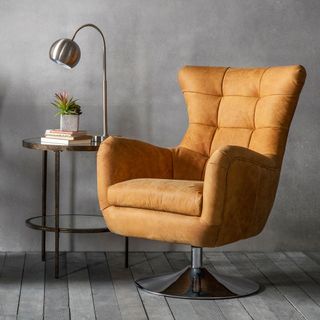 orange sofa chair on grey wooden floor grey wall and table lamp