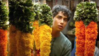 Suraj Sharma peeks out from carrot looking flower arrangements in Life of Pi.
