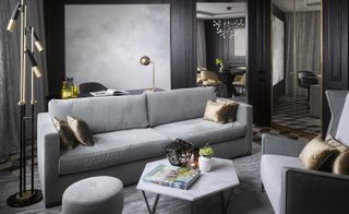 Grey lounge area featuring sofa and chair, hexagonal coffee table, and art deco lighting