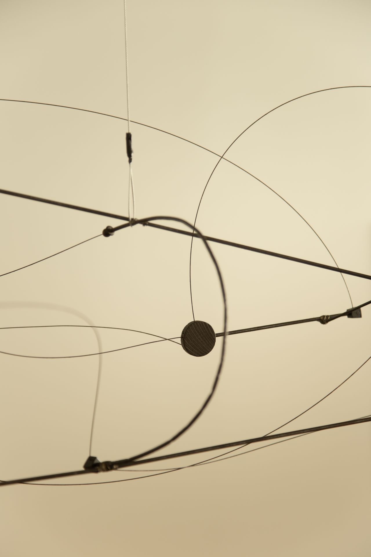 A geometric, minimalist mobile in iron floats in a white room.