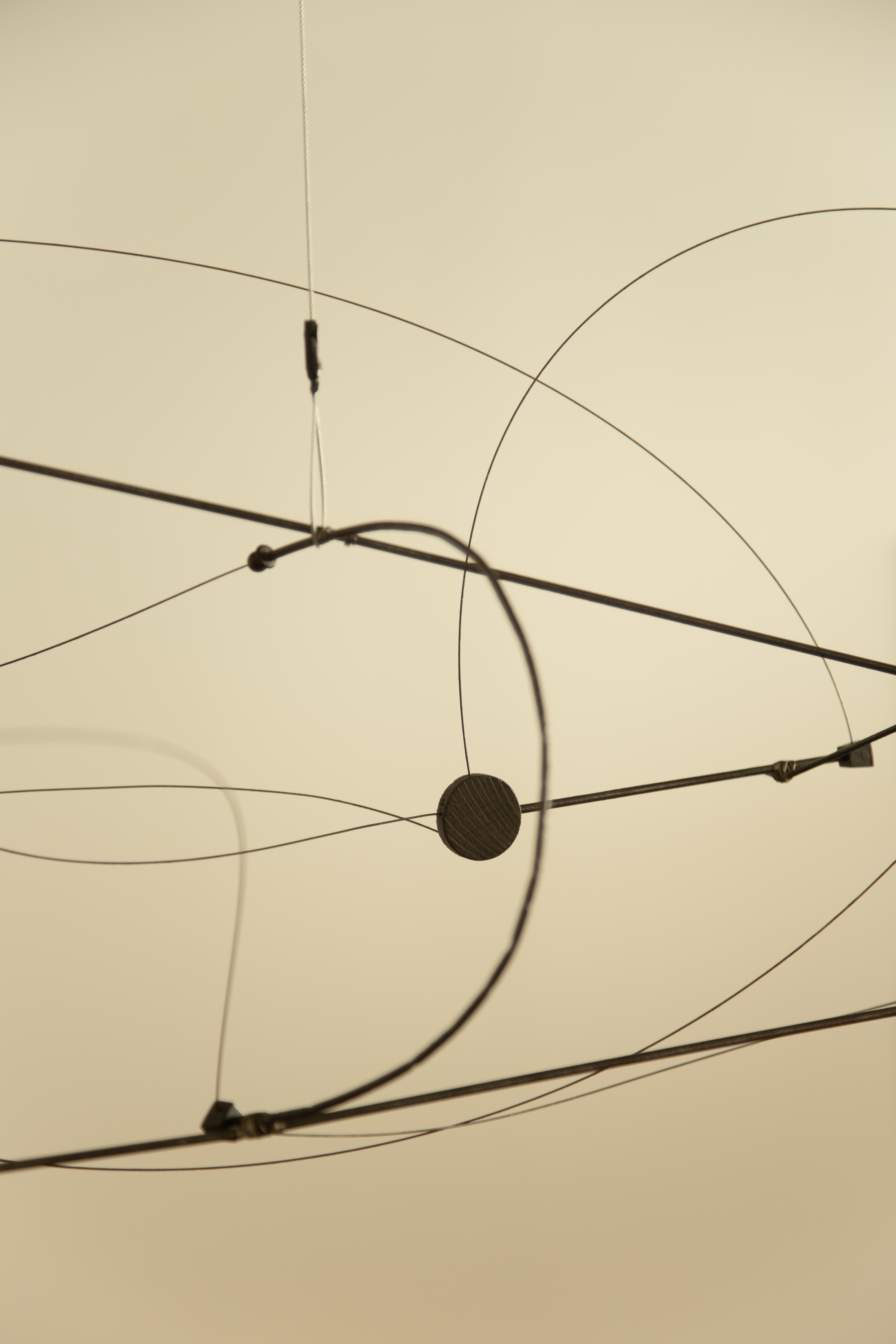 A geometric, minimalist mobile in iron floats in a white room.