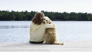 Women hugging dog on jetty: best things about owning a dog