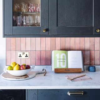 black kitchen cabinets with pink tiles and white worktop