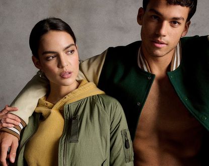 Man stood with arm around woman both in bomber jackets