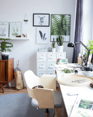 a Home office in a small white bedroom, with lots of natural artwork on the walls