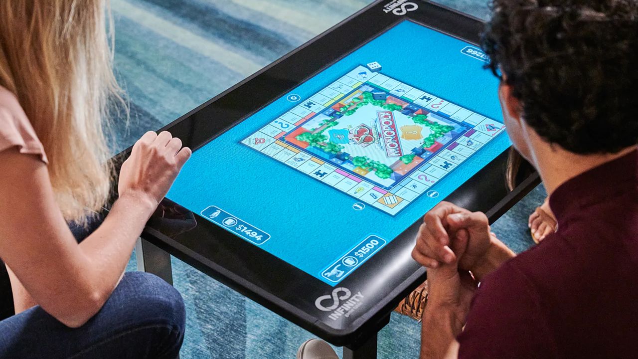 Infinity board game table in use by family playing Monopoly