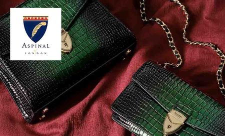 Aspinal of london logo placed over an image of two green scaly shoulder bags on red cloth