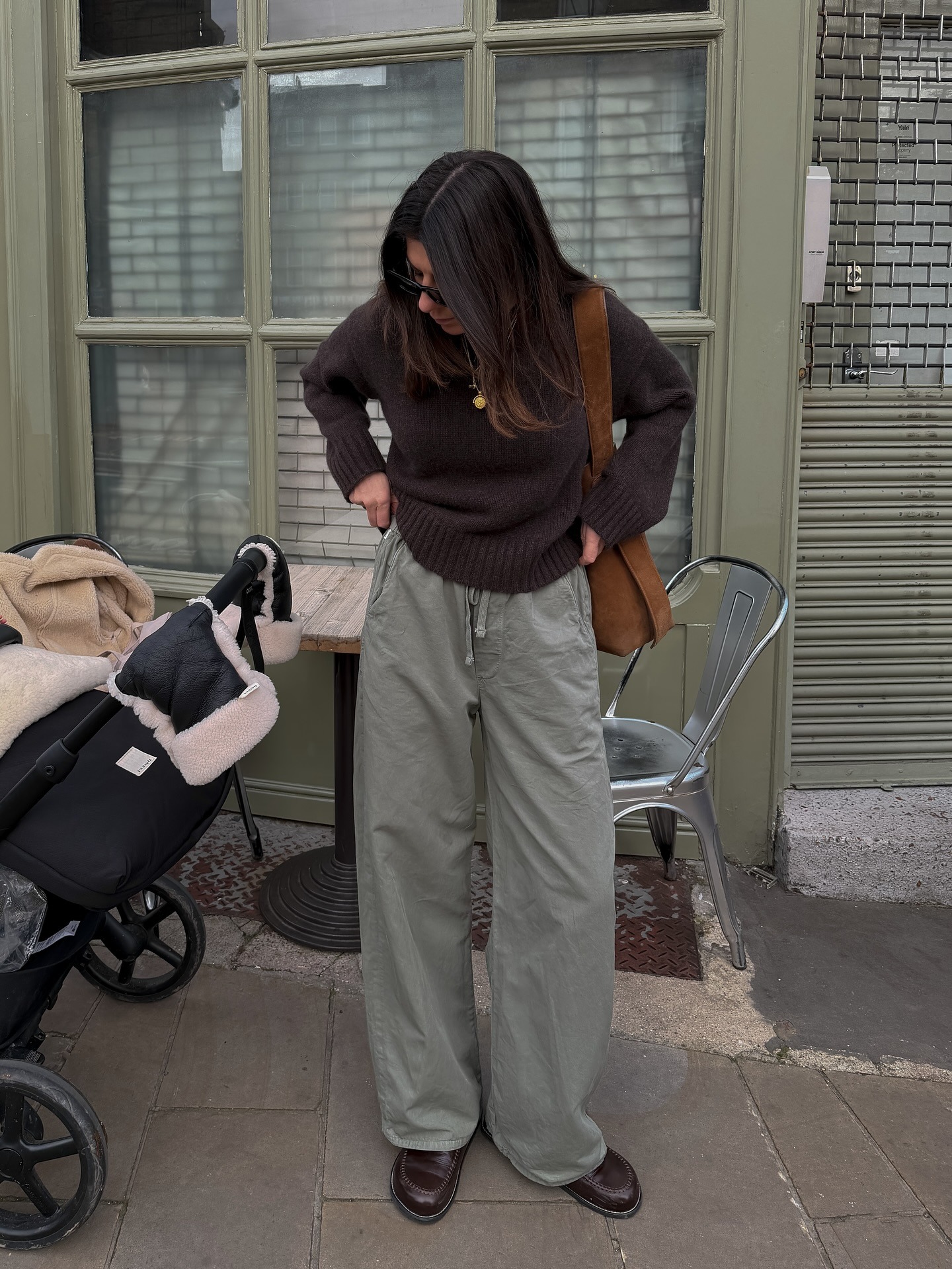 Woman on the street wearing a brown knitted jumper, green trousers and loafers.