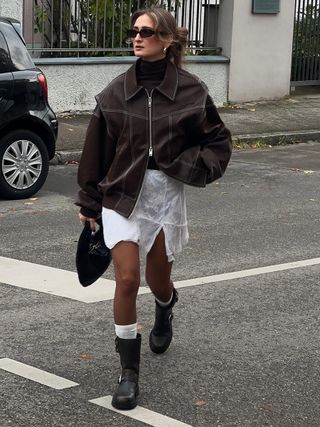 woman wearing white lace skirt with brown moto boots and brown jacket
