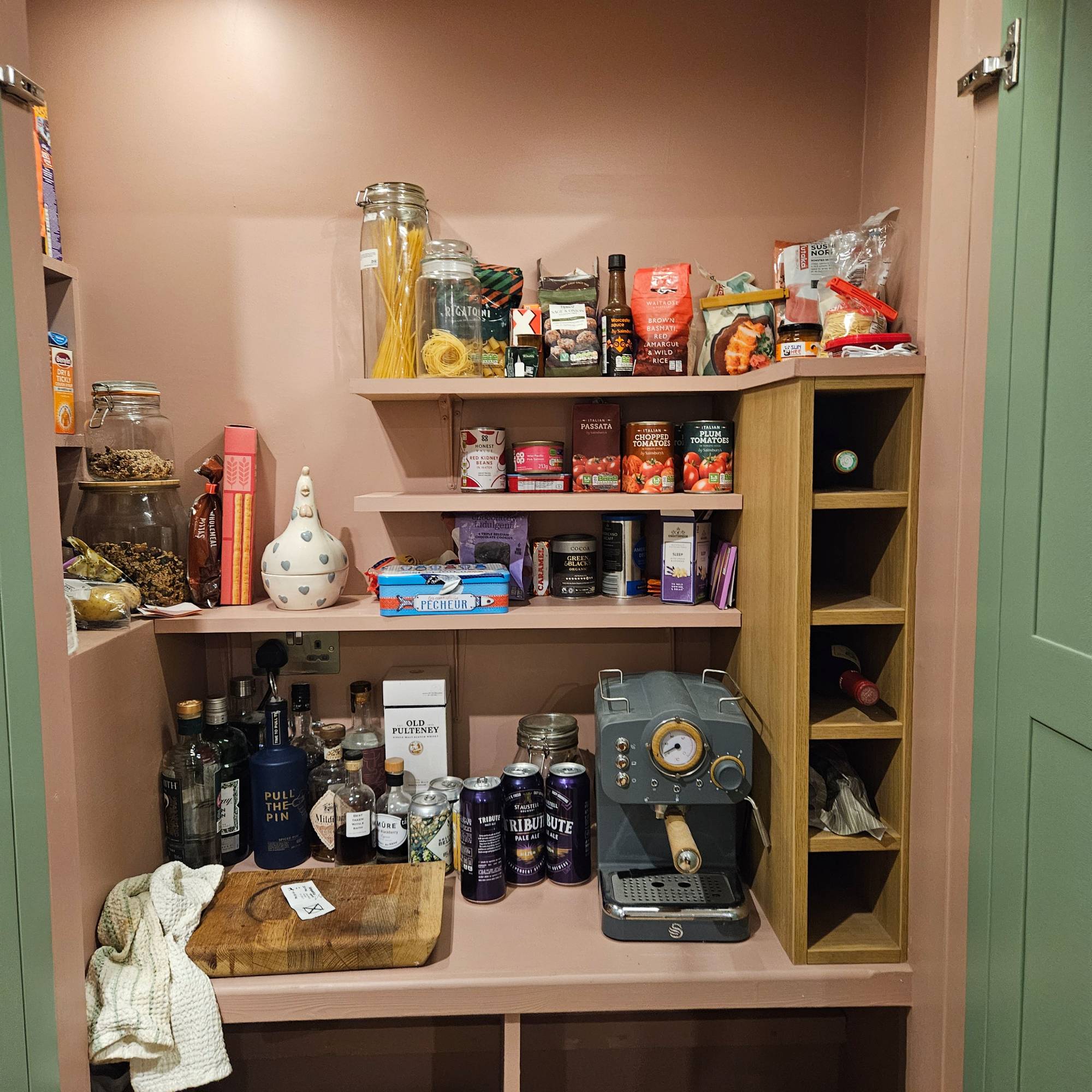 pink pantry with bottles, a coffee machine and chopping board
