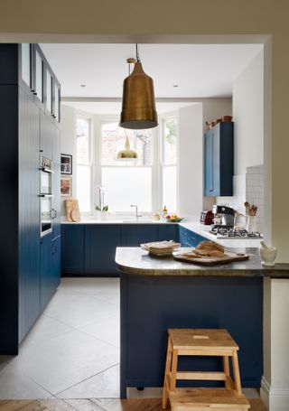 Small kitchen with dark blue cabinets with a peninsula breakfast bar with wood work surface/countertop