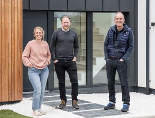 Lori and Tom with Kevin McCloud outside their new home.