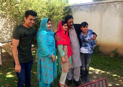 Pakistan's Nobel Peace Prize winner Malala Yousafzai, center, poses for a photograph with her family members at her native home during a visit to Mingora, the main town of Pakistan Swat Valle