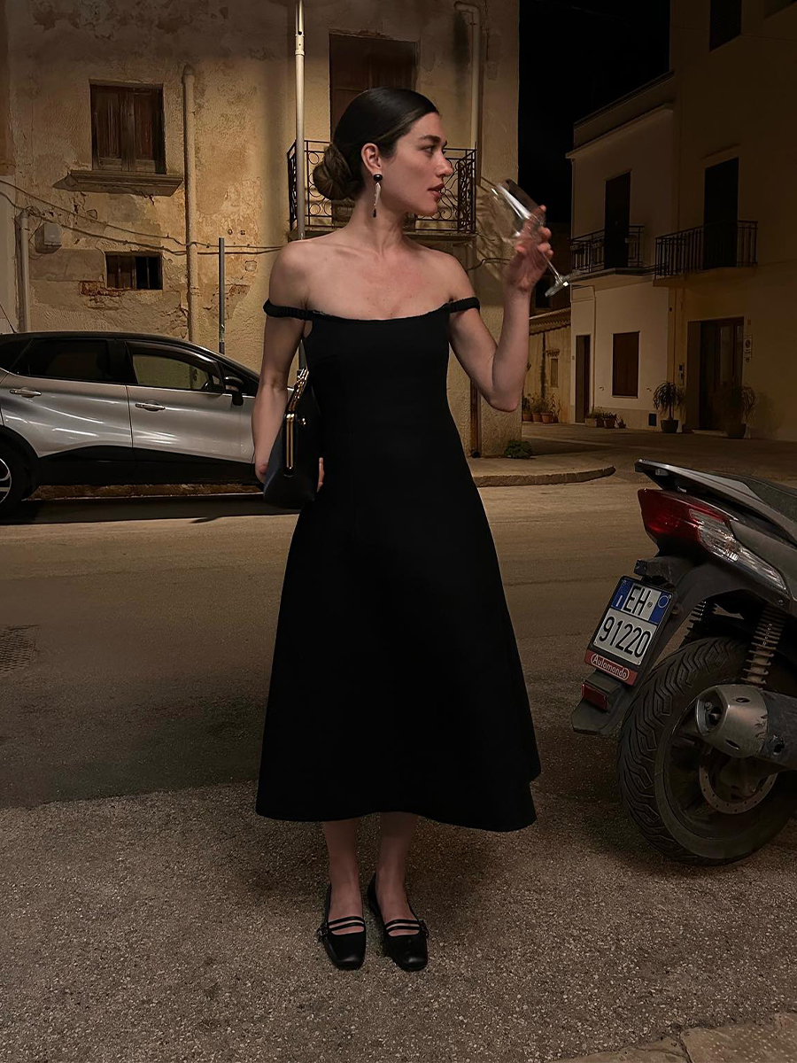 image of a woman wearing a black Khaite midi dress and flats